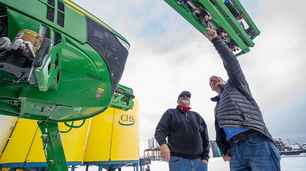 Two man talking by a self-propelled sprayer
