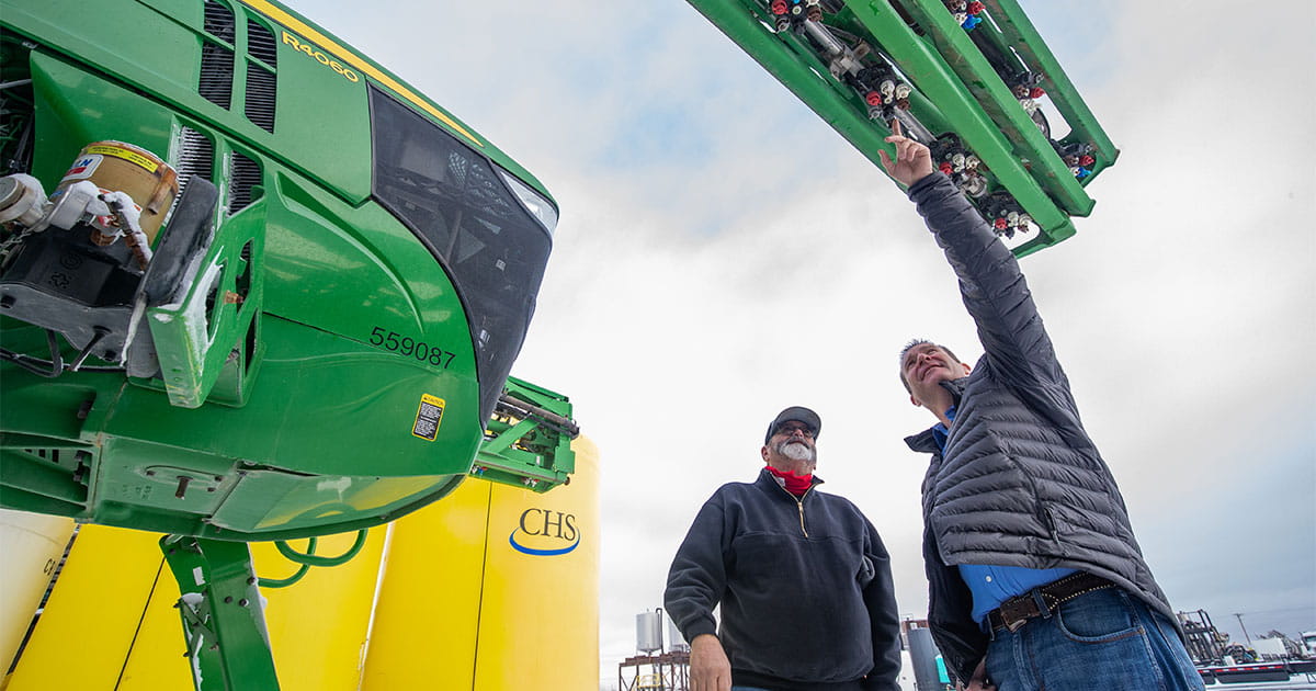 Two man talking by a self-propelled sprayer