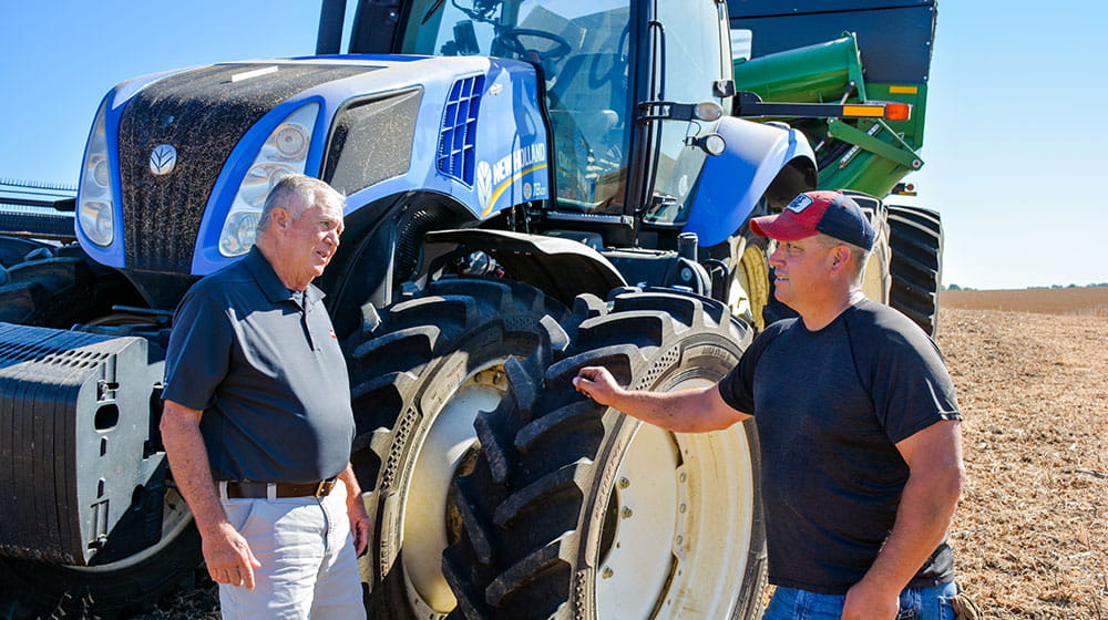 Two men talking by a tractor.