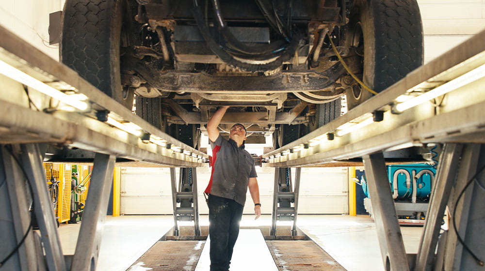 Man inspecting the bottom of a vehicle on risers