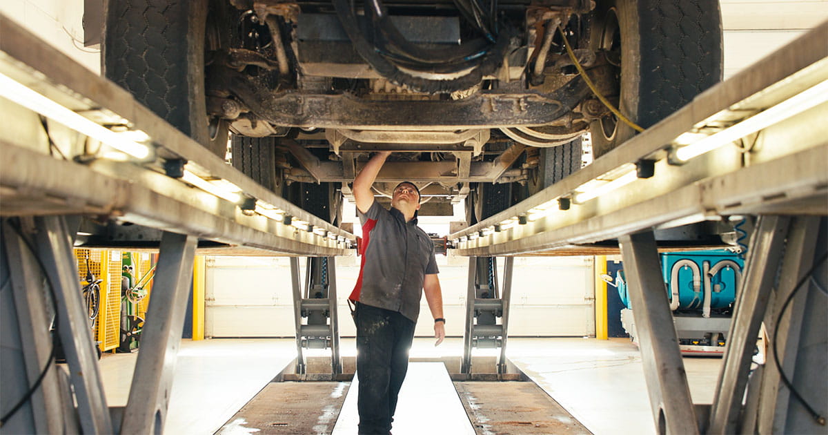 Man inspecting the bottom of a vehicle on risers