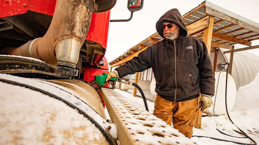 Man fueling truck from fuel tank during winter