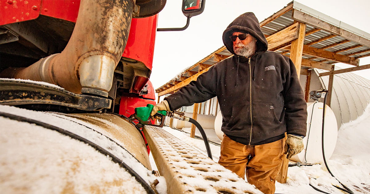 Man fueling truck from fuel tank during winter