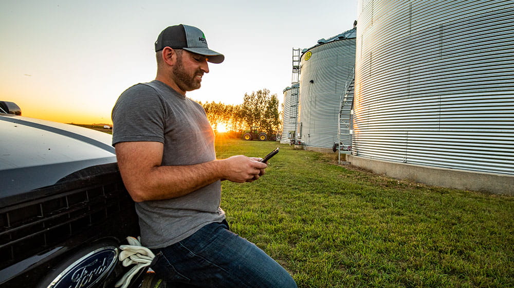 Man on his phone leaning against his truck.