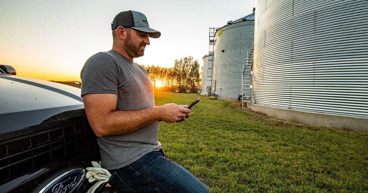 Man on his phone leaning against his truck. 