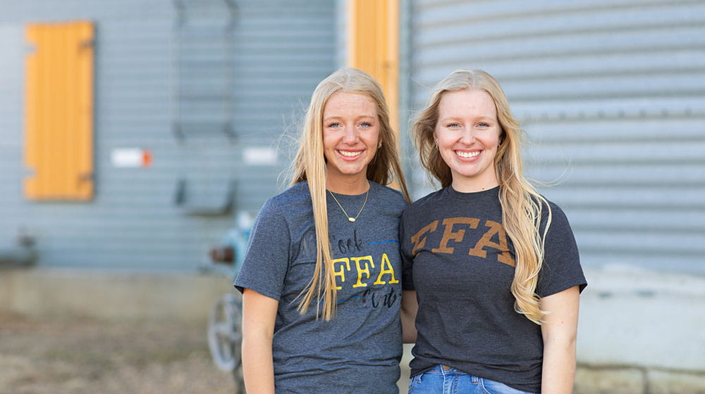 Two young women standing in front of a grain bin