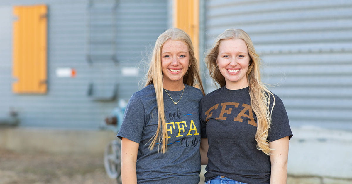 Two young women standing in front of a grain bin