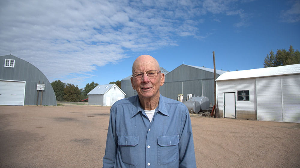 Man standing in front of farm buildings