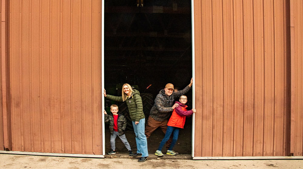 Young family of four pushing open shed doors