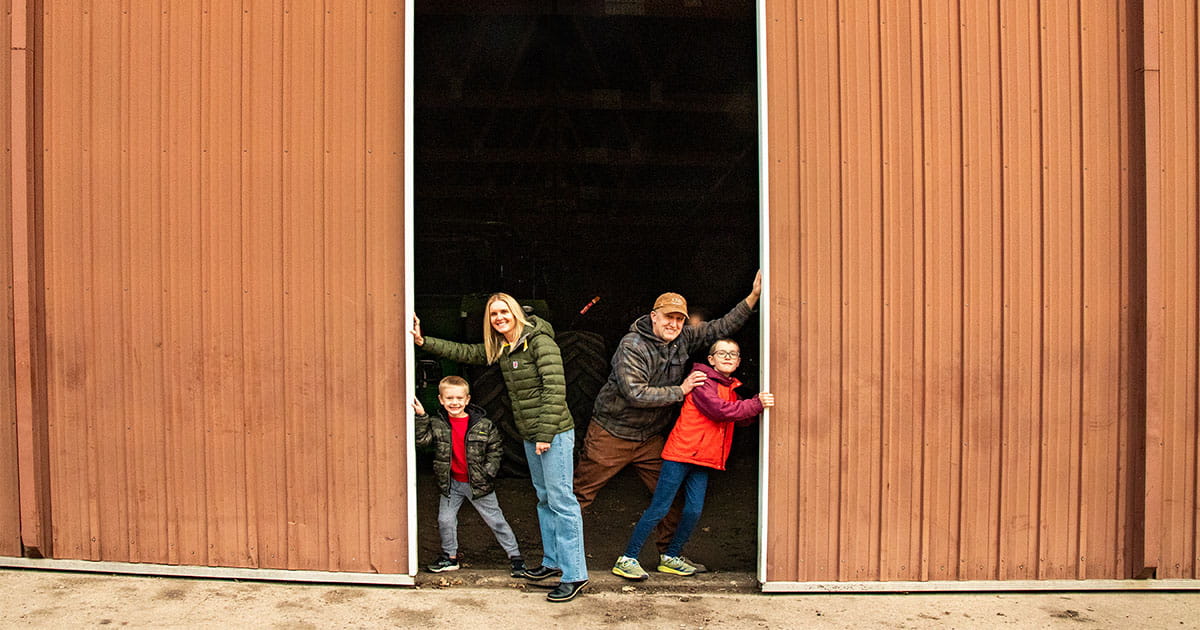 Young family of four pushing open shed doors