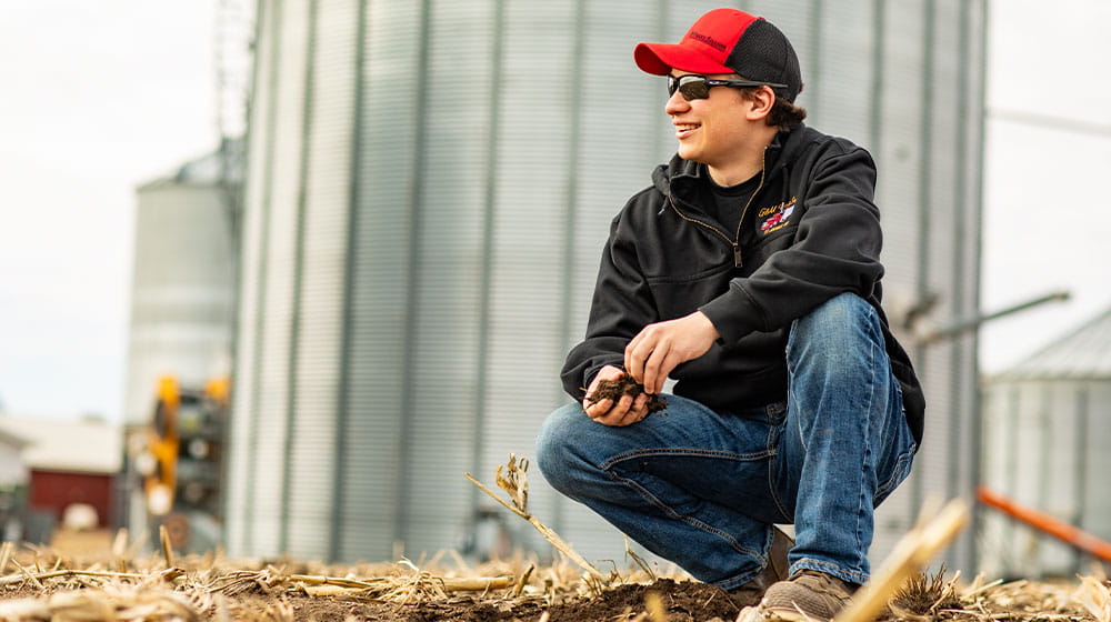 Man kneeling in a corn field before planting