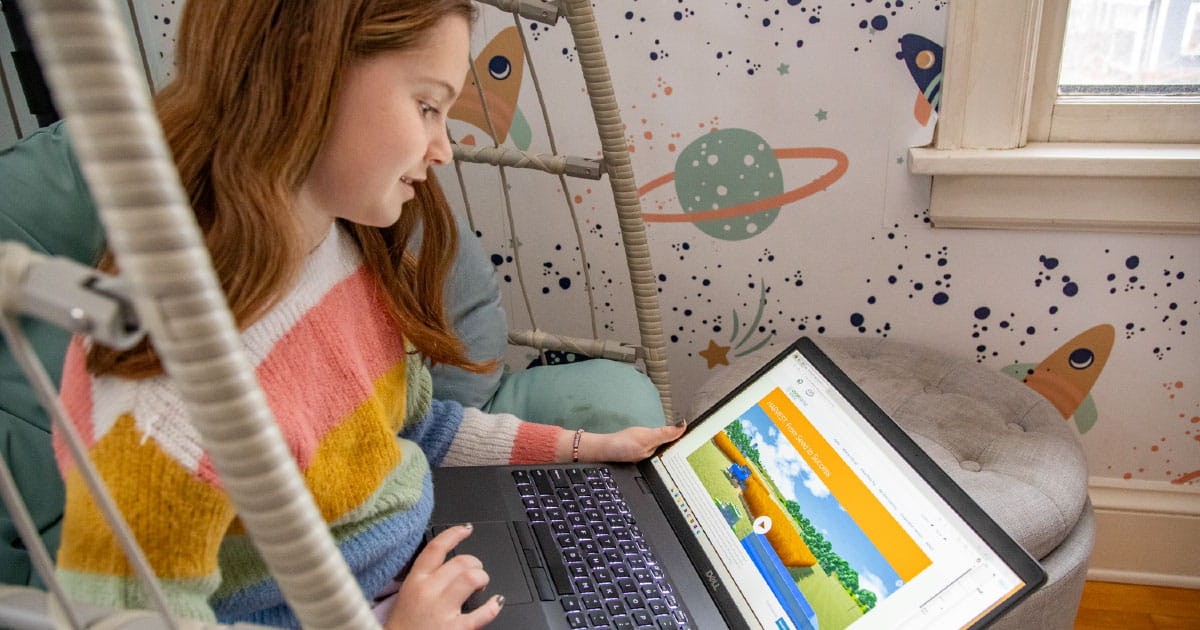 Child playing interactive farming game on laptop