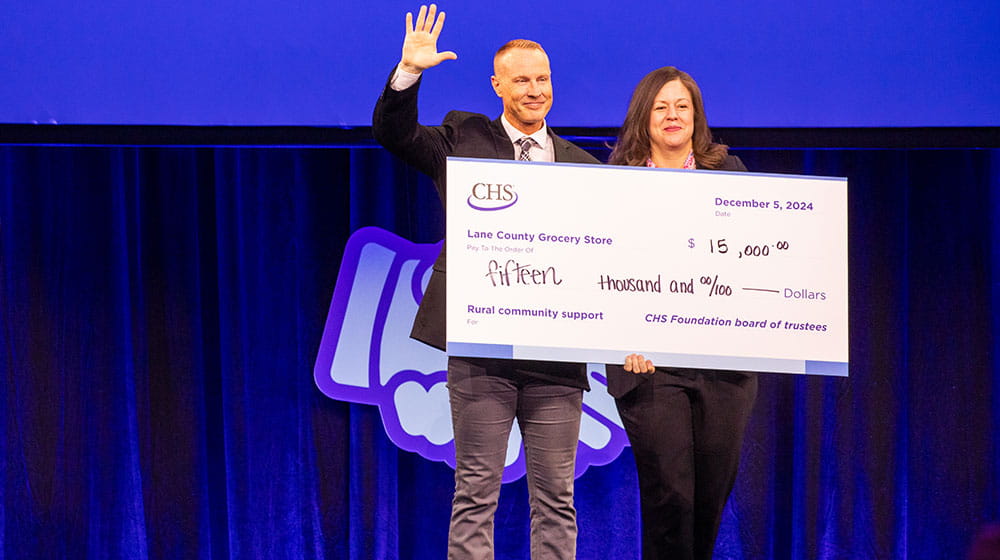 Several people standing on a stage holding large novelty checks.