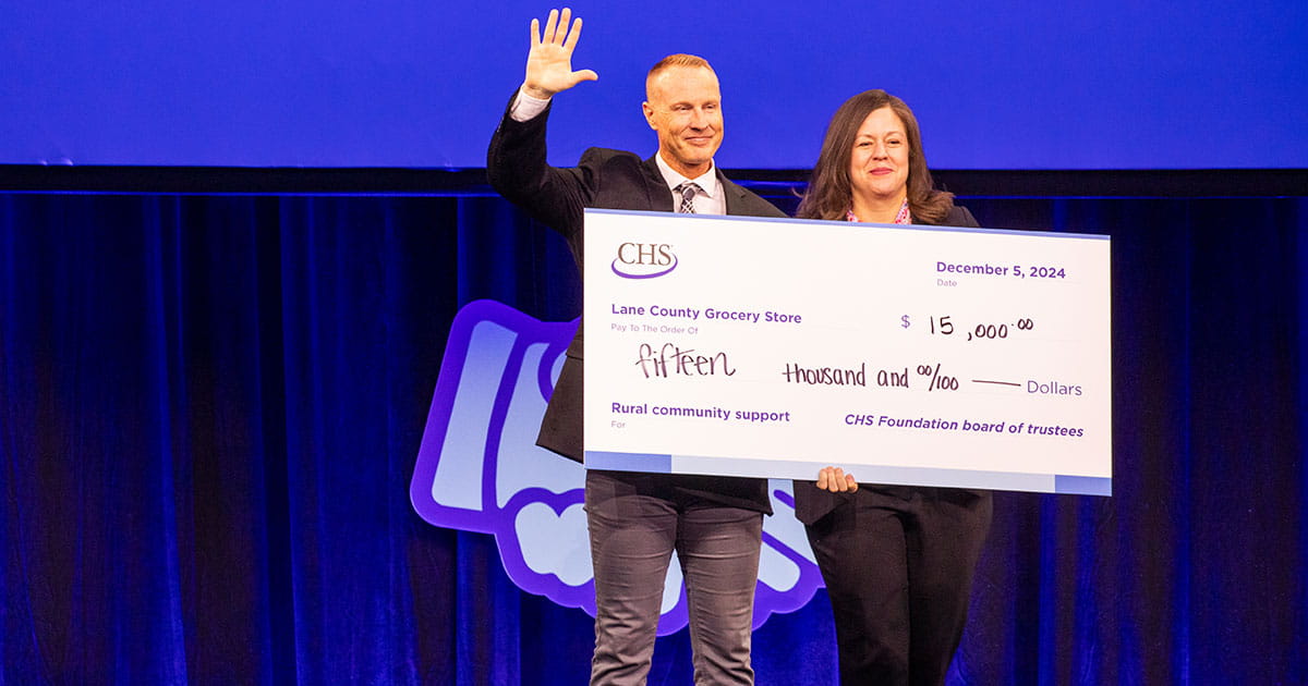 Several people standing on a stage holding large novelty checks.