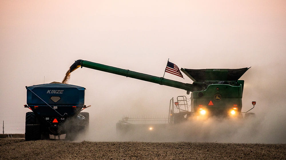 Combine harvesting field at dusk