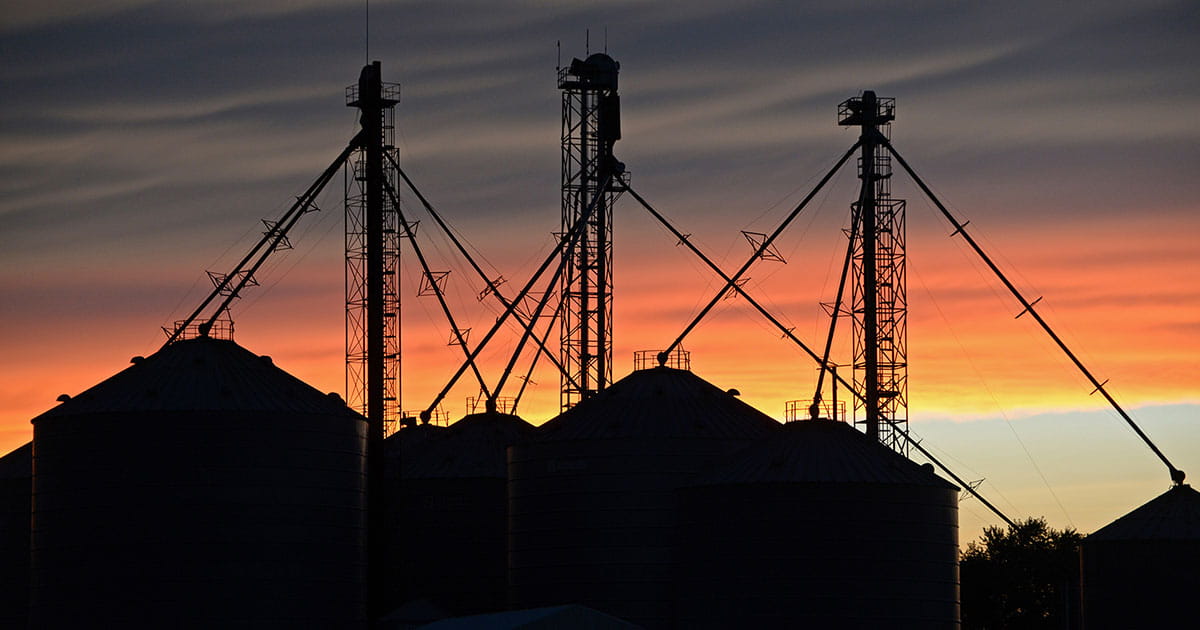 Grain bins with a sunset in the background. 