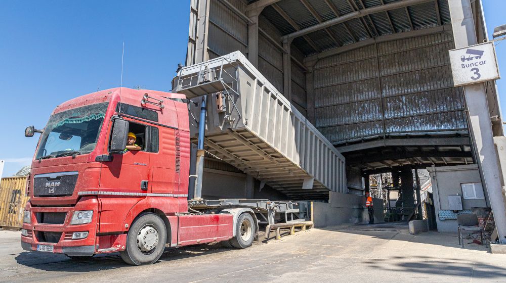 A truck with its trailer tilted up unloads grain.