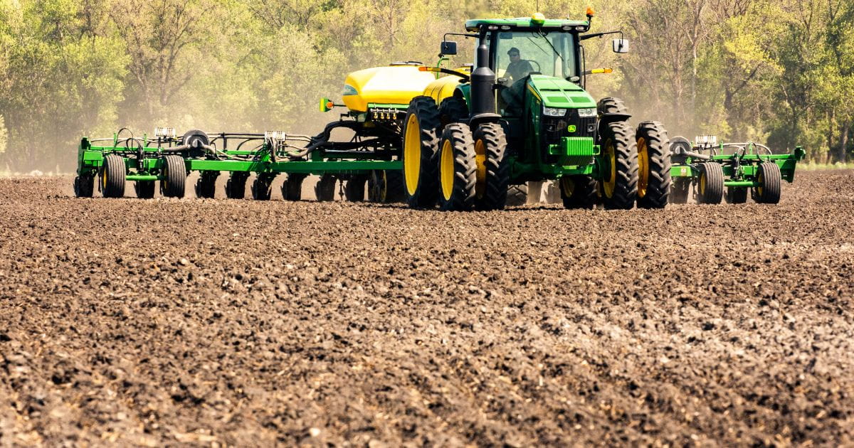Tractor pulling a planter and fertilizer unit.