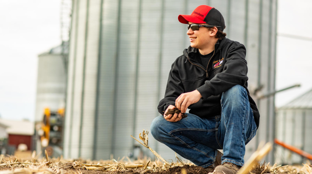Man in hat and sunglasses in front of grain bins